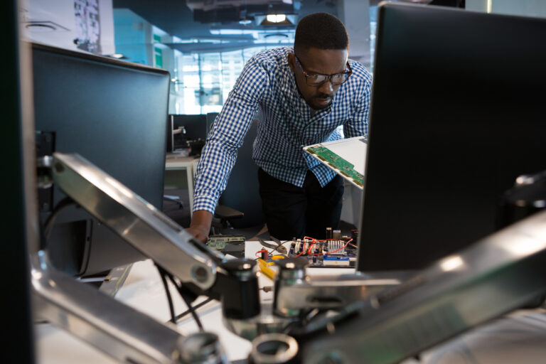 Computer engineer repairing motherboard at desk in office